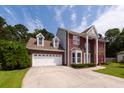 Charming two-story brick home featuring a two-car garage, red shutters, and beautiful landscaping at 8522 Long Meadow Dr, Charleston, SC 29420