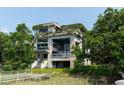 Modern waterfront home with lush greenery, multi-level balconies, and private dock access at 905 Palm Blvd, Isle of Palms, SC 29451