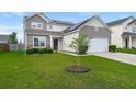 Two-story home features manicured lawn, neutral siding, stone accents, and attached two-car garage at 9711 Tackle St, Ladson, SC 29456
