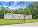 Inviting single-story home featuring a cozy front porch with white railings and a well-maintained lawn on a sunny day at 1051 Cooper Store Rd, Moncks Corner, SC 29461