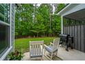 Inviting back patio features relaxing chairs and a grill, perfect for outdoor enjoyment with wooded view at 2402 Brackish Dr, Mount Pleasant, SC 29466