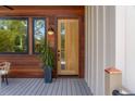 Inviting entryway with a natural wood door, wood siding, modern light fixture, and potted plant at 1012 E Erie Ave, Folly Beach, SC 29439