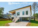 Modern home with elevated design, wood accents, driveway, and well-maintained landscaping at 1012 E Erie Ave, Folly Beach, SC 29439