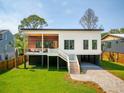 Modern home with unique architecture, featuring elevated design, wood accents, and a lush green lawn at 1012 E Erie Ave, Folly Beach, SC 29439