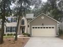 Two-story home with tan siding, dark shutters, and an attached garage in a residential area with a well kept yard at 1330 Somersby Ln, Mount Pleasant, SC 29466