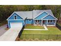 Aerial view of blue home showing the garage, front porch with seating, and black fence surrounding the property at 1543 Scott Hill Rd, James Island, SC 29412