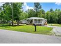 Inviting single-story home with a covered porch, gravel driveway, and lush green lawn at 208 General Moultrie Dr, Bonneau, SC 29431