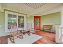 Inviting front porch with rocking chairs, bench, and view of the lush surroundings at 22 Beachwood East, Isle of Palms, SC 29451