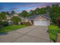 Inviting home with a manicured front lawn, mature shrubs, and a convenient two-car garage at 261 Sweet Alyssum Dr, Ladson, SC 29456