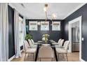 Elegant dining room with dark walls, a glass table, modern chandelier and bright, airy windows at 327 Megans Bay Ln, Charleston, SC 29492