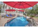 Inviting backyard pool area with red umbrellas, lounge chairs, and lush landscaping at 3805 Adrian Way, Mount Pleasant, SC 29466