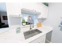 Close up of the kitchen sink and countertop, showcasing white cabinets and modern fixtures at 45 Sycamore Ave # 611, Charleston, SC 29407