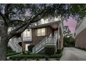 Charming brick townhome with white stairs, lush landscaping, and mature trees, during twilight hours at 622 Windermere Blvd # D, Charleston, SC 29407