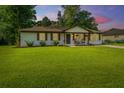 Charming white brick home with a well-manicured lawn, rocking chairs, and lovely landscaping at dusk at 114 Bailey Dr, Summerville, SC 29485