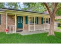 Inviting front porch with brick facade, teal door, and white railing at 114 Stewart St, Goose Creek, SC 29445