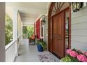 Welcoming front porch with cozy seating, lovely plants, and a stylish wooden door at 16 Fairway Village Ln, Isle of Palms, SC 29451