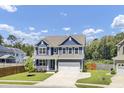 Charming two-story home features a manicured lawn, blue siding, and a two-car garage at 203 Plowden Mill Ct, Summerville, SC 29485