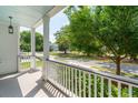 Inviting front porch featuring white railings and a tranquil view of the neighborhood street and lush greenery at 2242 Dewees Creek Dr, Mount Pleasant, SC 29466