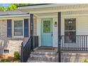 Close-up of the front porch showcasing a teal door, brick steps, and black railing at 300 Oklahoma Pl, Ladson, SC 29456