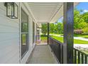 Inviting covered porch with black railings and a view of the lush, green front yard at 300 Oklahoma Pl, Ladson, SC 29456