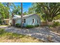 A light blue home with a brick chimney is surrounded by mature trees and has a concrete driveway at 309 Padgett Loop, Walterboro, SC 29488