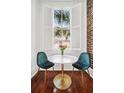 Dining area with a table with two chairs next to a window with white shutters and exposed brick at 33 Pitt St # 3, Charleston, SC 29401