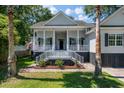 Inviting home exterior with a classic white porch, stairs, pillars, black shutters, and an American flag at 3872 James Bay Road Rd, Johns Island, SC 29455