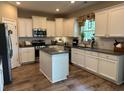 Well-lit kitchen with stainless steel appliances, granite countertops, white cabinets, and hardwood floors at 677 Redbud Ln, Summerville, SC 29486
