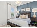 Modern bedroom featuring a large wooden bed frame, stylish lighting, and a calming blue accent wall at 760 Meadowbrook Ln, Summerville, SC 29486