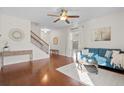Sun-filled living room featuring hardwood floors, blue sofa, ceiling fan, and stairway to second floor at 9747 Seed St, Ladson, SC 29456