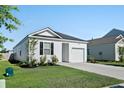 View of a one-story home featuring white siding, black shutters, green grass, and an attached one-car garage at 1014 Peridote Way, Ladson, SC 29456