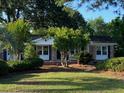 Inviting single-story home with brick accents, a covered porch, and mature landscaping at 121 Camelot Dr, Goose Creek, SC 29445
