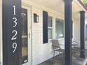 Inviting front porch of a charming house with white brick and black accents at 1329 Camp Rd, Charleston, SC 29412