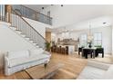 Open-concept living space with hardwood floors, modern staircase, and view into the kitchen at 1474 Blue Cascade Dr, Mount Pleasant, SC 29464