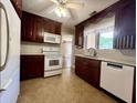Well-lit kitchen featuring dark wood cabinets, white appliances, a window over the sink, and vinyl floors at 2173 Annie Laura Ln, Mount Pleasant, SC 29466