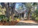Quaint home with large mature trees, professional landscaping, and a welcoming covered porch entry at 2655 Gnarled Pine, Seabrook Island, SC 29455