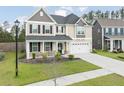 Inviting two-story home with a landscaped yard, covered front porch, and attached two-car garage at 283 Saxony Loop, Summerville, SC 29486