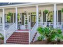 Inviting front porch with decorative columns, rocking chairs, stylish lanterns, and lush greenery at 3130 Pignatelli Cres, Mount Pleasant, SC 29466