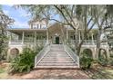 Beautiful home with elegant staircase leading to a covered porch, surrounded by lush landscaping at 4702 Blockhouse Ln, Hollywood, SC 29449