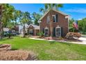 All brick home with tidy lawn and mature landscaping, including palm trees with American flag in yard at 569 Pointe Of Oaks Rd, Summerville, SC 29485