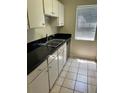 Galley kitchen with sleek, black countertops, white cabinets and stainless steel sink at 6 Town Park Ln # C, Charleston, SC 29412