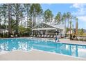 Inviting pool area with shaded lounge seating and a charming pool house in a landscaped setting at 708 Breakers Reef Ln, Huger, SC 29450