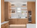 Bright butler's pantry featuring custom oak cabinets, open shelves, elegant marble backsplash, and a wine refrigerator at 71 Moultrie St, Charleston, SC 29403