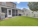 A well-kept backyard boasts artificial grass, a white picket fence, screened-in porch, and a patio area perfect for outdoor entertaining at 1005 Washitonia Way # B, Charleston, SC 29492