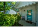 Inviting front entrance with a vibrant turquoise door, lush greenery, and a cozy sitting area at 2016 Wild Flower Ln, Charleston, SC 29414
