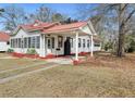 Exterior of a charming home featuring a red roof, covered side entrance, and lush yard at 222 E Main St, Moncks Corner, SC 29461