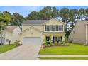 Charming two-story home with yellow siding, black shutters, well-manicured lawn and beautiful landscaping at 230 Sweet Alyssum Dr, Ladson, SC 29456