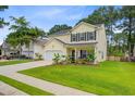 Charming two-story home with yellow siding, black shutters, well-manicured lawn and beautiful landscaping at 230 Sweet Alyssum Dr, Ladson, SC 29456