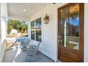 Inviting front porch with rocking chairs, wood door, and white pillars, offering a cozy outdoor space at 3143 Vanessa Lynne Ln, Johns Island, SC 29455
