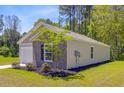 A side view of a well-maintained single-story home with brick accents and a manicured lawn at 407 Spruce Ivy St, Moncks Corner, SC 29461